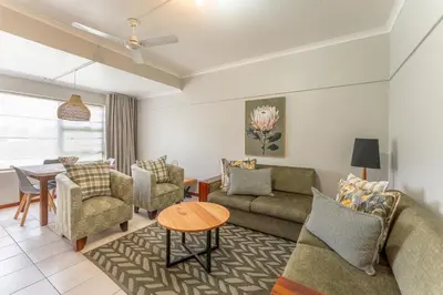 a living room with a couch and chairs and a table at Fairway Holiday Accommodation in Hermanus