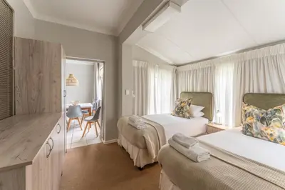 a hotel room with two beds and a desk at Fairway Holiday Accommodation in Hermanus