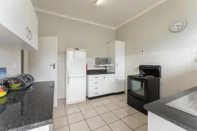 a white kitchen with a refrigerator and a stove at Fairway Holiday Accommodation in Hermanus