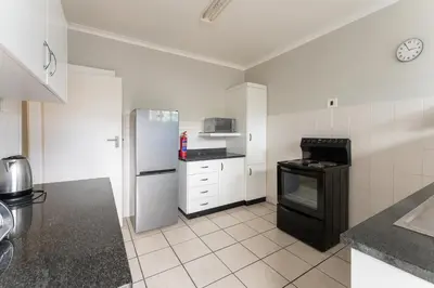 a kitchen with a refrigerator and a stove at Fairway Holiday Accommodation in Hermanus