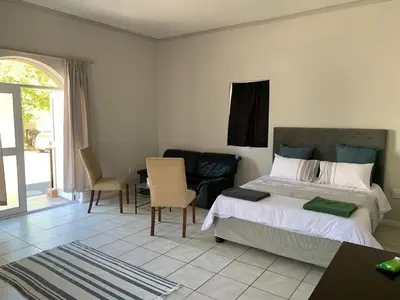 a bedroom with a bed and a table and chairs at Le Grec Wine Tram Apartment #3 in Franschhoek