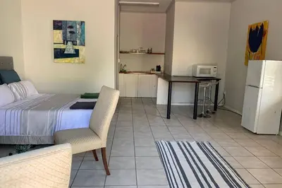 a bedroom with a bed and a kitchen with a refrigerator at Le Grec Wine Tram Apartment #3 in Franschhoek