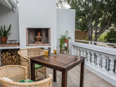 a table and chairs on a balcony with a fireplace at Ridge House in Hermanus