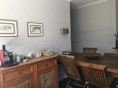 a dining room with a wooden table and chairs at Olive Cottage in Hermanus