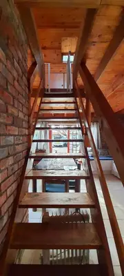 a wooden staircase in a room with a brick wall at Cozy Cottage +/- 500m from the beach in Cape Town