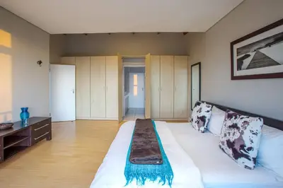 a large bedroom with a large white bed and wooden cabinets at Gecko House in Pringle Bay