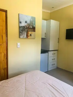 a small kitchen with a bed and a refrigerator at ALIAHIDI in Cape Town