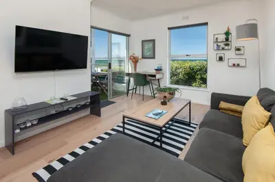 a living room with a couch and a tv and a table at 64 Whalerock Estate in Hermanus