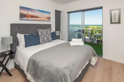 a bedroom with a large bed and a balcony at 64 Whalerock Estate in Hermanus