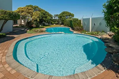 a large swimming pool with a brick walkway around it at 64 Whalerock Estate in Hermanus