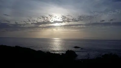 a view of the ocean with the sun in the sky at Thundering waves in Bettyʼs Bay