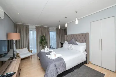 a bedroom with a large bed and a living room at The Model House in Cape Town