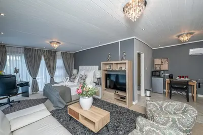 a large living room with a bed and a tv at The Model House in Cape Town
