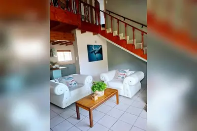 a living room with two couches and a staircase at Mond Kleine Guest House in Kleinmond