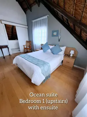 a bedroom with a large white bed with blue pillows at Mond Kleine Guest House in Kleinmond