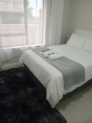 a bedroom with a bed with two towels on it at Jackie’s 3 bedroomed secure beach front apartment Strand Golden Mile in Strand