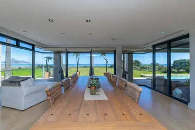 a living room with a wooden table and a couch at Villa Paradis - ocean front with views to behold! in Cape Town