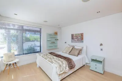 a white bedroom with a bed and a window at Villa Paradis - ocean front with views to behold! in Cape Town