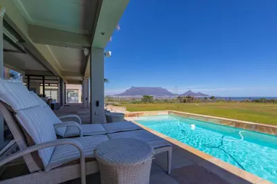 a house with a swimming pool and some chairs at Villa Paradis - ocean front with views to behold! in Cape Town