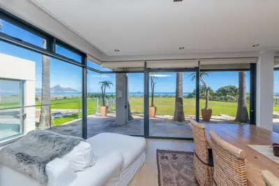 a dining room with a table and glass walls at Villa Paradis - ocean front with views to behold! in Cape Town