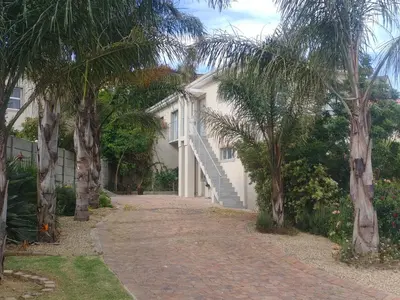 a white house with palm trees in front of it at Zebra Place in Cape Town