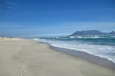 a sandy beach with a view of the ocean at Waters Breakaway in Bloubergstrand