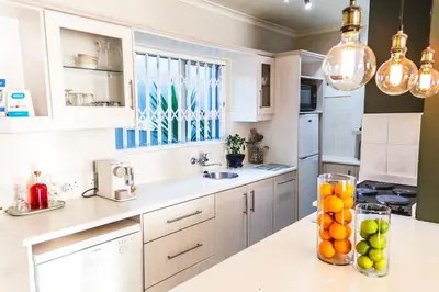 a kitchen with white cabinets and a bowl of fruit on a counter at Seagull Hermanus in Hermanus