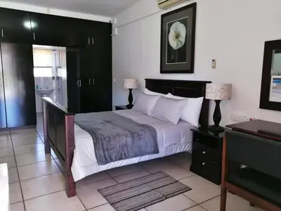 a bedroom with a large bed with white pillows at Sunset Boulevard Riverlodge in Paarl