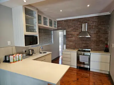 a kitchen with white cabinets and a brick wall at Balmoral Lodge in Bellville