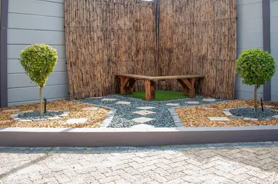 a wooden bench in a courtyard with two trees at Balmoral Lodge in Bellville