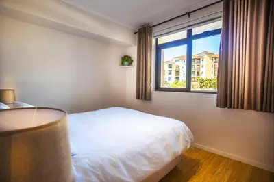 a bedroom with a white bed and a window at Portifino On Lake G16 The Island Club in Cape Town