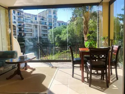 a balcony with a table and chairs and a large window at Portifino On Lake G16 The Island Club in Cape Town
