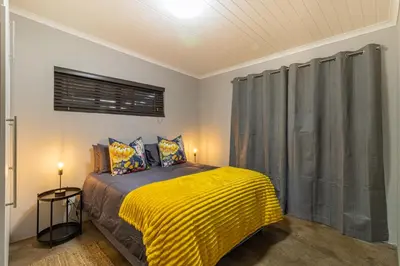 a bedroom with a bed with a yellow blanket at Steenbok farm cottages -Mongoose cottage in Wolseley