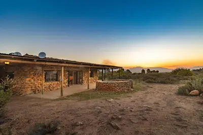 a stone house with the sunset in the background at Steenbok farm cottages -Mongoose cottage in Wolseley