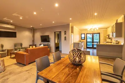 a living room with a wooden table and a couch at Steenbok farm cottages -Mongoose cottage in Wolseley