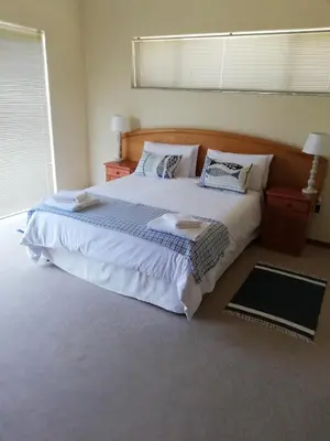 a bedroom with a large bed with white sheets and pillows at C the C - Holiday Home in Hermanus