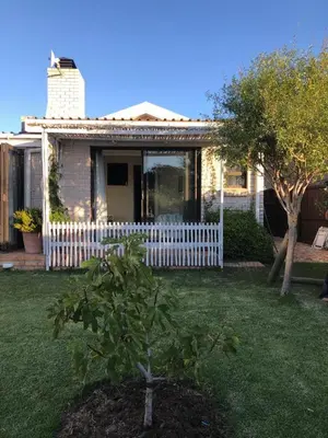 a house with a white fence and a tree in the yard at The West Wing guest suite. Pringle Bay. in Pringle Bay