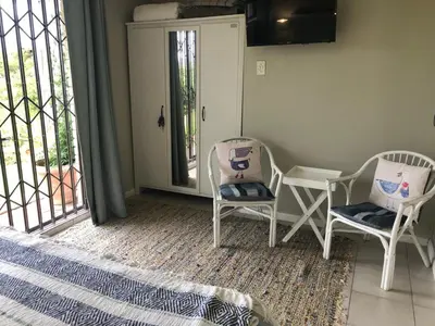 a room with two chairs and a table and a window at The West Wing guest suite. Pringle Bay. in Pringle Bay