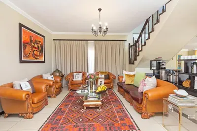 a living room with leather couches and a table at Kwantu Guesthouse 1 in Cape Town
