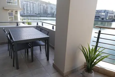 a table and chairs on a balcony with a view of the water at Little Venice Self Catering in Bellville