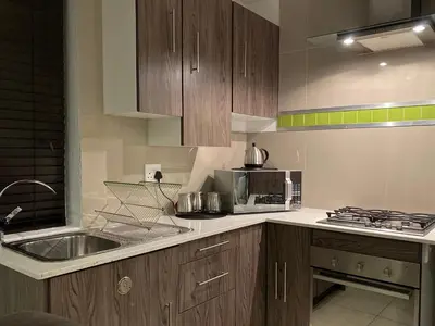 a kitchen with a sink and a microwave at On the GBay Villa in Gordonʼs Bay