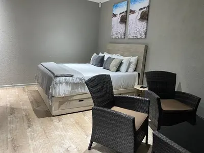 a bedroom with a bed with two chairs and a table at On the GBay Villa in Gordonʼs Bay