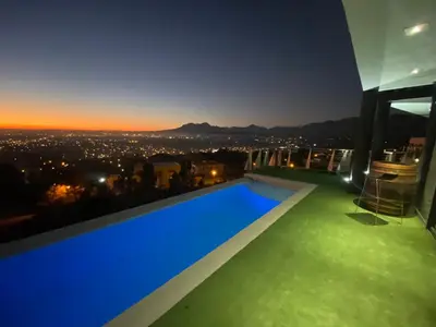a swimming pool on top of a building at night at On the GBay Villa in Gordonʼs Bay