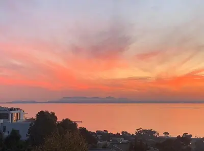 a sunset over a body of water with a city at On the GBay Villa in Gordonʼs Bay