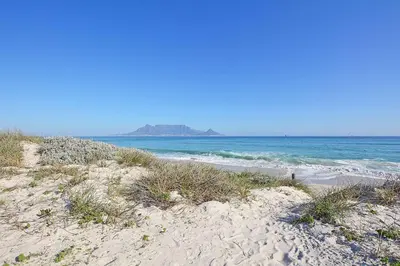 a sandy beach with the ocean in the background at 6 Atlantic Port - Cosy, modern 2-bedroom apartment - Blouberg in Bloubergstrand