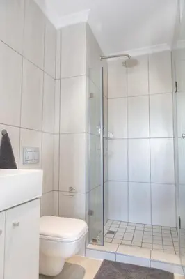 a white bathroom with a shower and a toilet at 6 Atlantic Port - Cosy, modern 2-bedroom apartment - Blouberg in Bloubergstrand