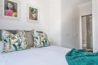 a bedroom with a white bed with pillows at 6 Atlantic Port - Cosy, modern 2-bedroom apartment - Blouberg in Bloubergstrand