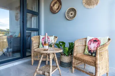 a bottle of wine on a table next to two chairs at 6 Atlantic Port - Cosy, modern 2-bedroom apartment - Blouberg in Bloubergstrand
