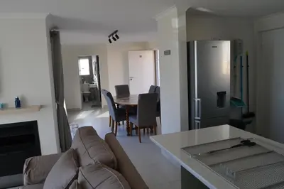 a kitchen and living room with a table and chairs at Hermanus Beach Club - Le Maree House 18 in Hermanus