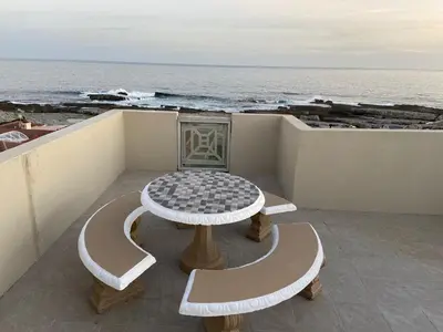 a table and benches on a balcony overlooking the ocean at CView in Hermanus